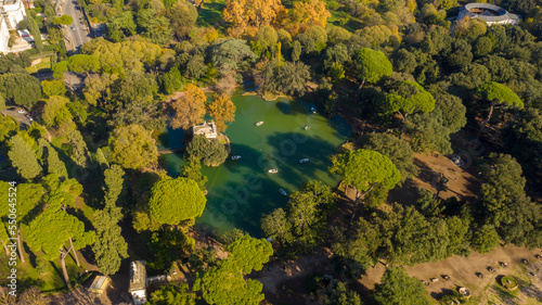 Fototapeta Naklejka Na Ścianę i Meble -  Aerial view of the small lake in Villa Borghese park. This pond is located in Rome, Italy. There are small row boats with people.
