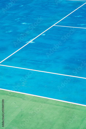 Deserted tennis court with greentrees in background in a public park on a sunny summer morning © yaophotograph