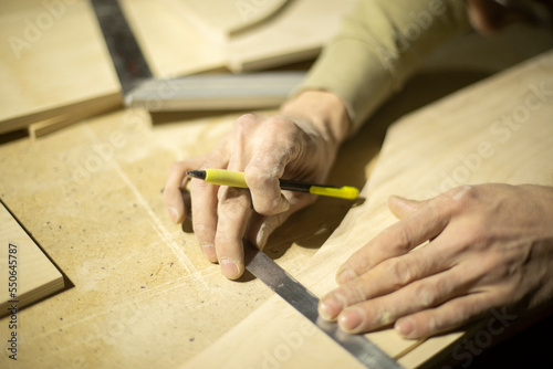 Guy marks board on ruler. Marking with pencil. Carpenter measures surface. Hands of master.