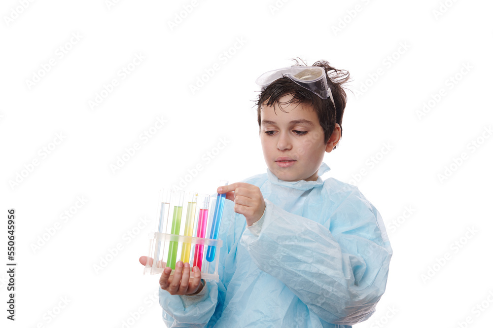 Close-up of multi-ethnic smart teenage boy, young pupil chemist scientist wearing a blue lab coat and goggles, with test tubes on tripod, conducting chemistry experiment, isolated on white background Close-up of multi-ethnic smart teenage boy, young pupil chemist scientist wearing a blue lab coat and goggles, with test tubes on tripod, conducting chemistry experiment, isolated on white background