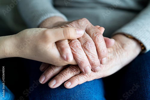 Young hand holding old hands of a woman