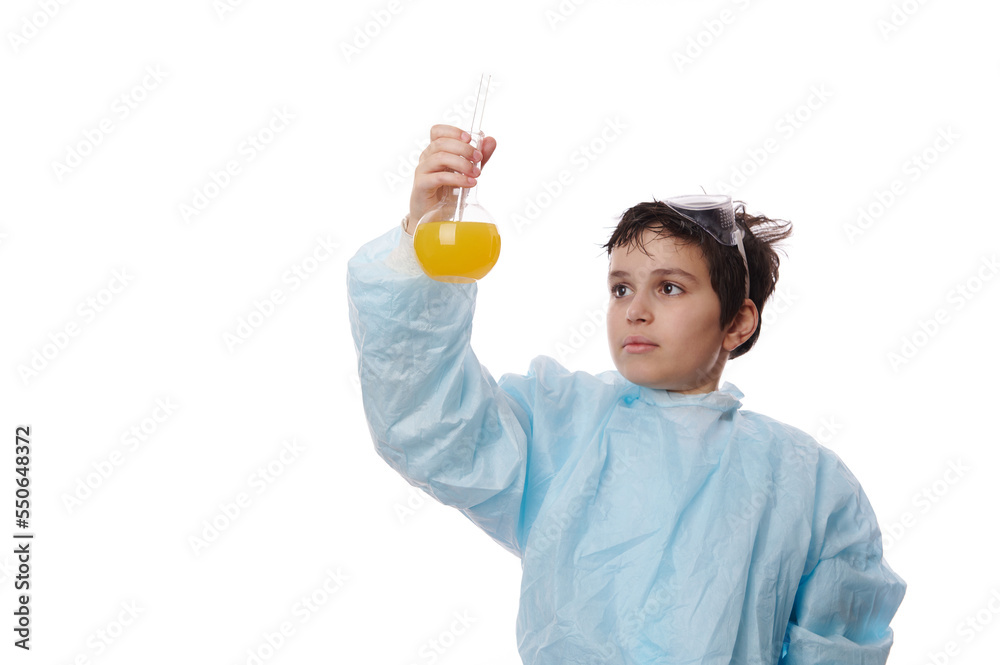Handsome Caucasian schoolboy, a scientist chemist in a white lab coat, holding glass laboratory flasks with chemicals, watching the reaction taking place between liquid and reagents. Chemistry class. Handsome Caucasian schoolboy, a scientist chemist in a white lab coat, holding glass laboratory flasks with chemicals, watching the reaction taking place between liquid and reagents. Chemistry class.