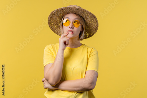 Thinking around woman on yellow background. Smart student girl finding answer or trying to remember what she forgot, memory concept