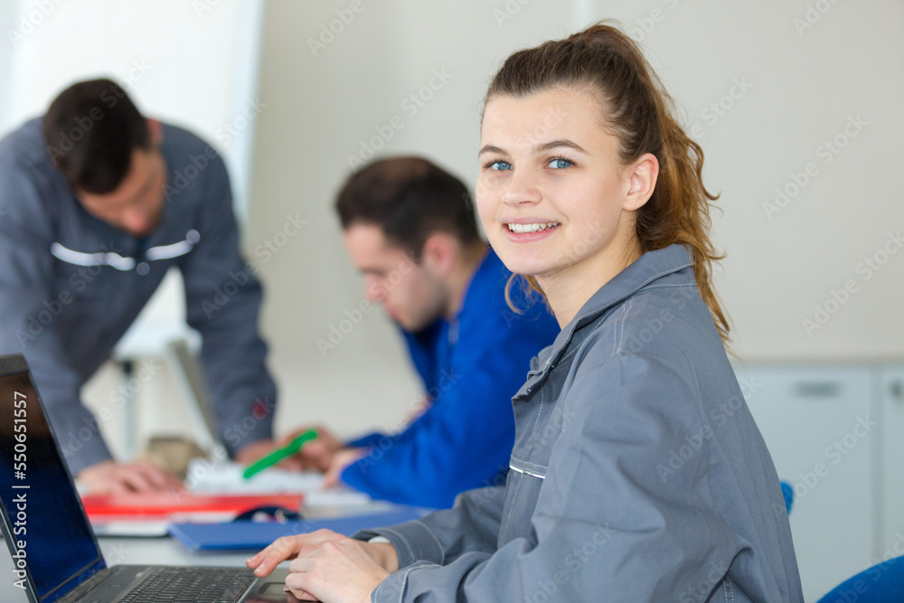 portrait of young female wearing overalls and using laptop portrait of young female wearing overalls and using laptop