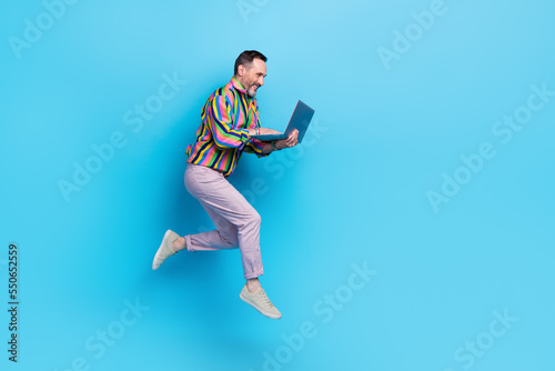 Full length photo of joyful glamour man using netbook read news feel young empty space isolated on blue color background