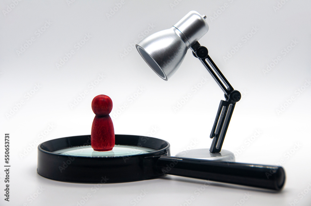 Red wooden figure on top of magnifying glass with white background. Selection concept Red wooden figure on top of magnifying glass with white background. Selection concept
