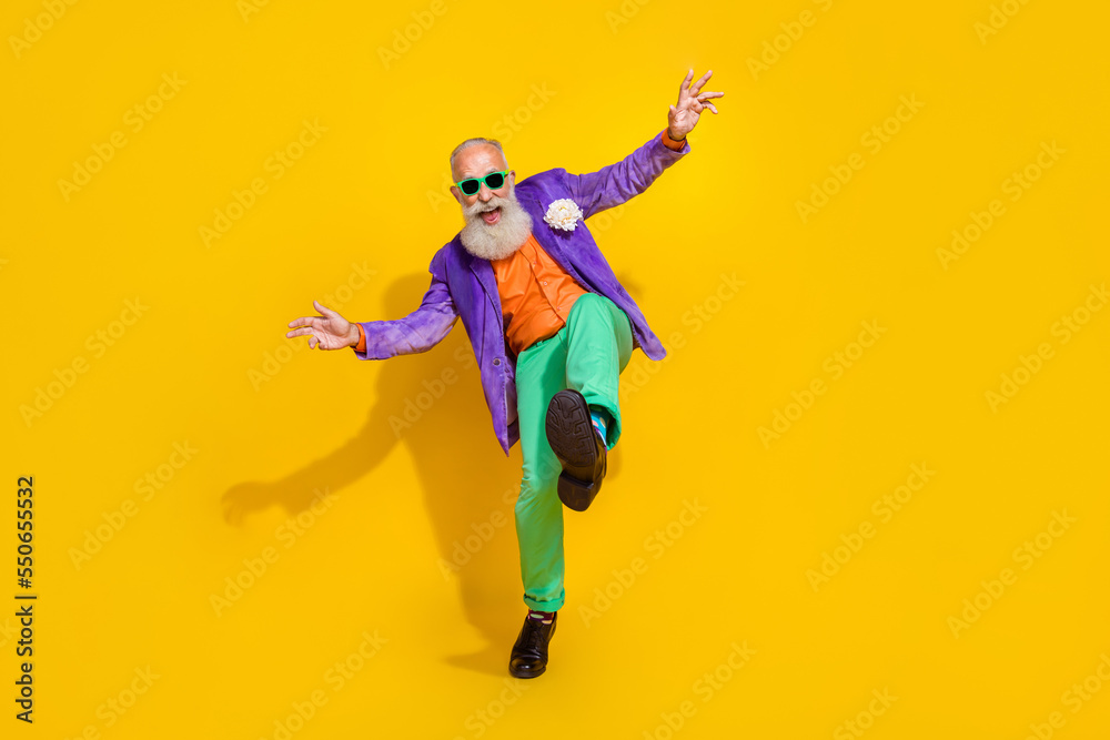 Full length photo of excited funky man wear purple velvet jacket having fun discotheque walking isolated yellow color background
