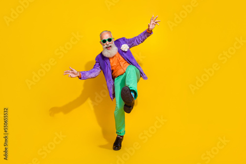 Fototapeta Naklejka Na Ścianę i Meble -  Full length photo of excited funky man wear purple velvet jacket having fun discotheque walking isolated yellow color background