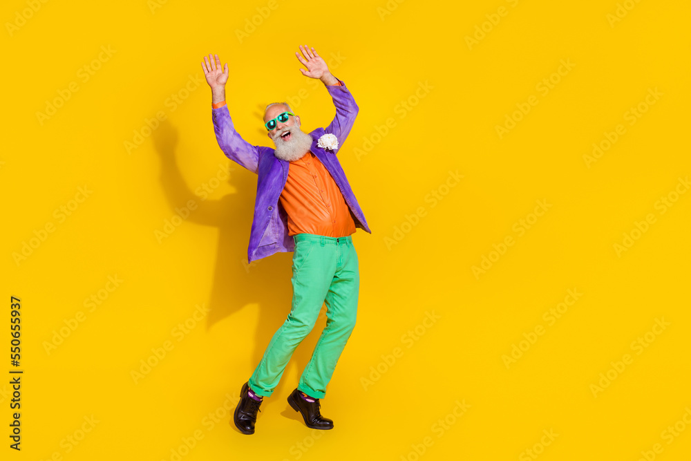 Full length photo of excited cool guy dressed violet velvet jacket rising hands enjoying disco isolated yellow color background Full length photo of excited cool guy dressed violet velvet jacket rising hands enjoying disco isolated yellow color background