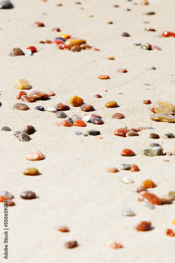 Sea stones amber yellow colored on natural fine beige  sand shore background, copy space. Natural colorful pebbles, monochrome Minimal nature summer landscape, beautiful beach, selective focus