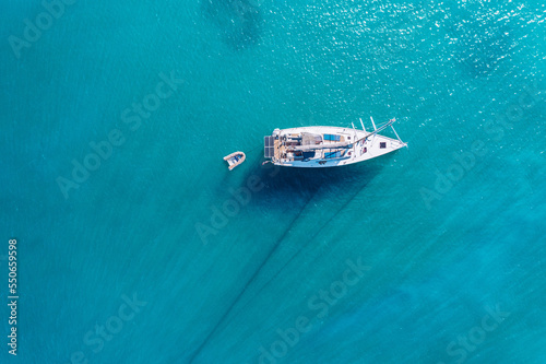 Yacht on lagoon at sunny day. Sailing boat. Yacht in the sea, aerial photography drone. Amazing yacht or sailing boat with a turquoise and transparent sea. Top view of the sailing boats in blue lagoon