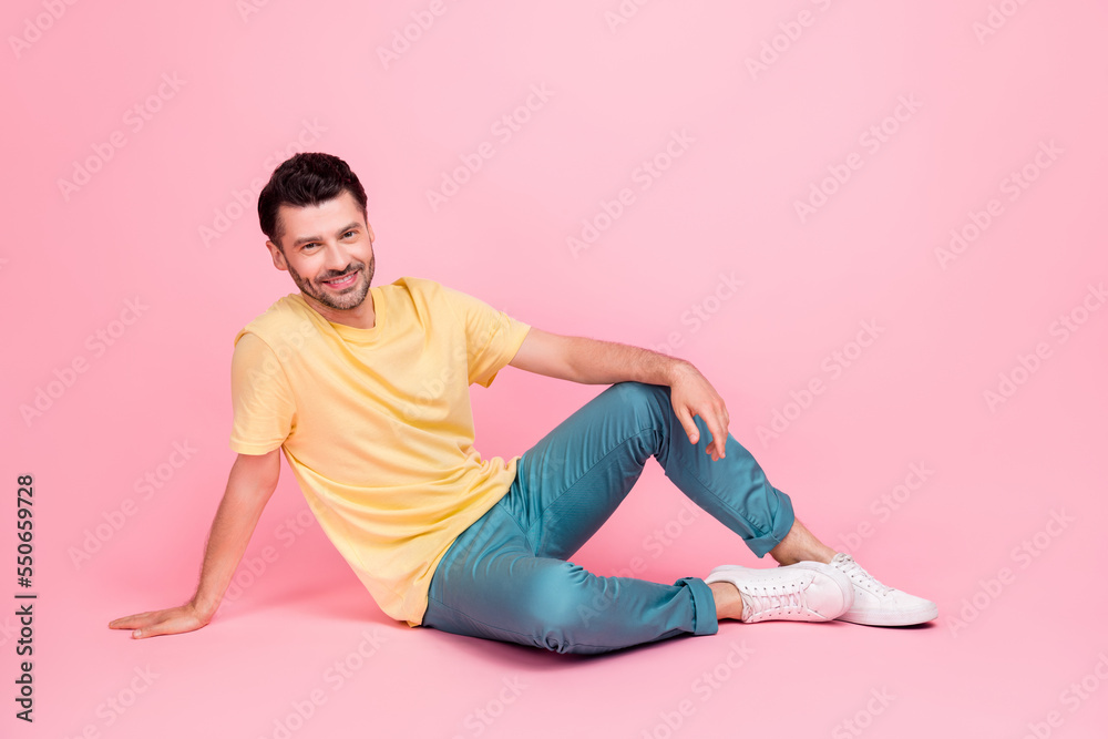 Photo of attractive good looking man sitting floor wear comfort yellow trendy clothes empty space isolated on pink color background Photo of attractive good looking man sitting floor wear comfort yellow trendy clothes empty space isolated on pink color background