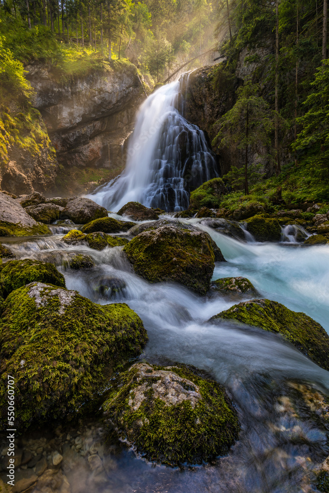 Fototapeta premium Gollinger Waterfall in Golling an der Salzach near Salzburg, Austria. Gollinger Wasserfall with mossy rocks and green trees, Golling, Salzburger Land, Austria.