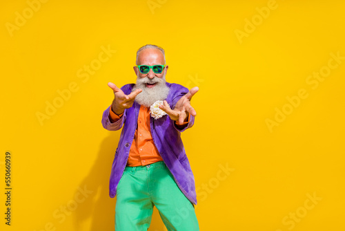 Photo of cheerful joyful pensioner wear trendy costume invite you join company club event empty space isolated on yellow color background