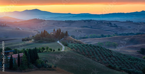 Fototapeta Well known Tuscany landscape with grain fields, cypress trees and houses on the hills at sunset