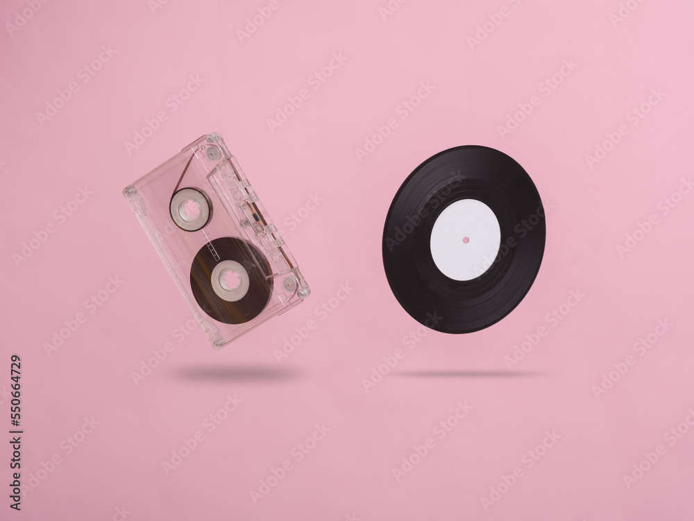 Audio cassette and vinyl record levitating on a pink background. Minimalism music concept Audio cassette and vinyl record levitating on a pink background. Minimalism music concept