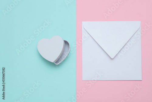 White envelope with a heart-shaped gift box on a pastel background. Valentine's day concept