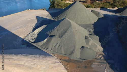 Industrial area for processing mining material, rock, stone for crushing machine. Manufacturing plant with hills of crushed stone, sand and gravel for construction. Heavy machinery conveyer.