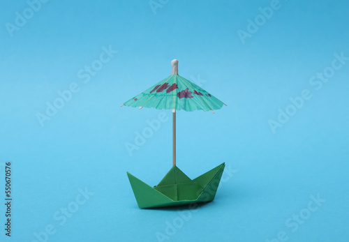 Paper boat with an umbrella on a blue background