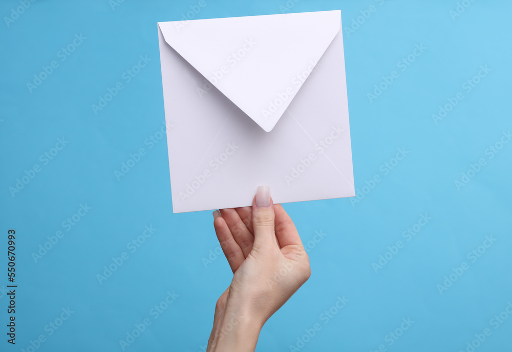 Woman's hand holding white envelope on a blue background