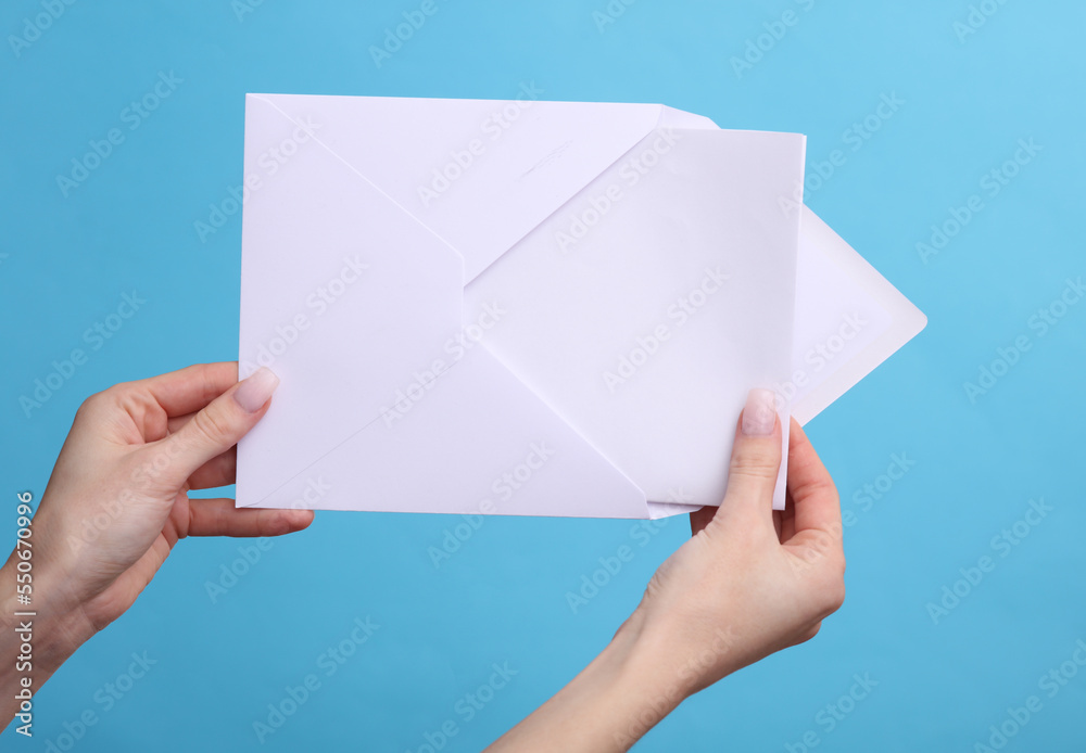 woman's hands holding white envelope with a letter on a blue background woman's hands holding white envelope with a letter on a blue background