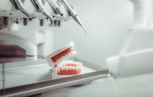 Human jaw model with dental tools drill in a dental clinic. Medicine, health, stomatology concept.