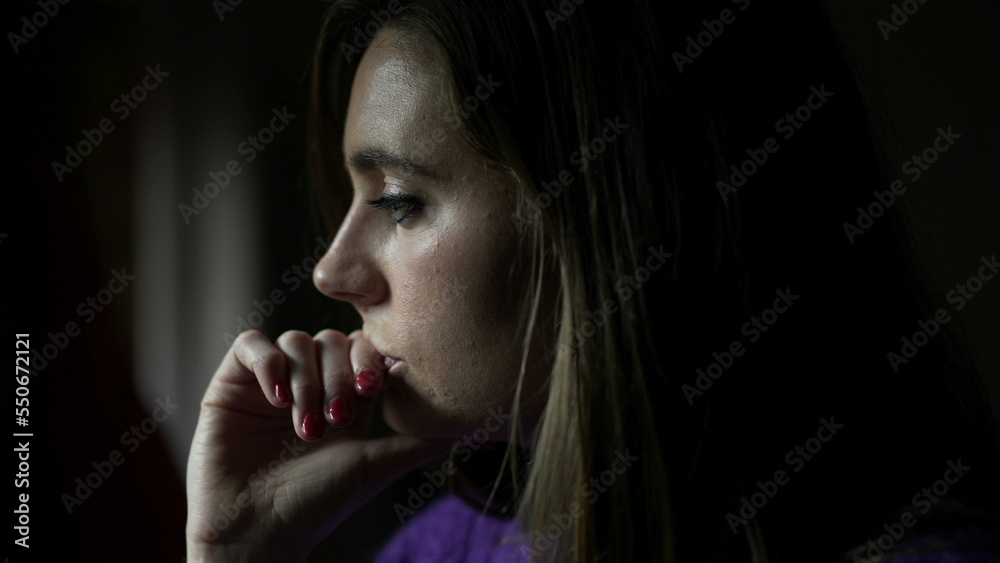 Thoughtful young woman standing by window thinking about life looking outside indoors Thoughtful young woman standing by window thinking about life looking outside indoors