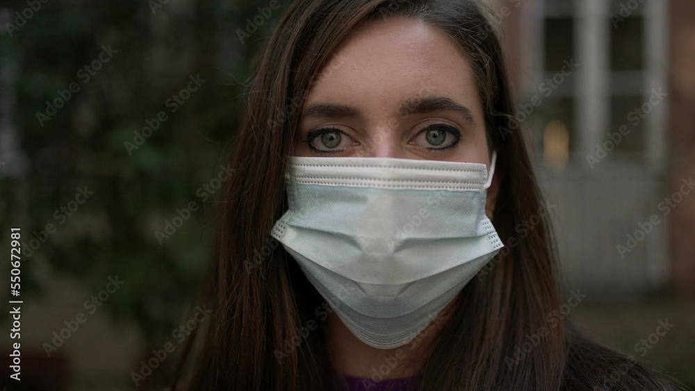 Woman wearing surgical covid-19 face mask standing outside looking at camera portrait Woman wearing surgical covid-19 face mask standing outside looking at camera portrait