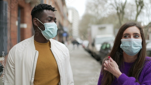 People wearing covid-19 face mask standing outside in street. black man and white woman