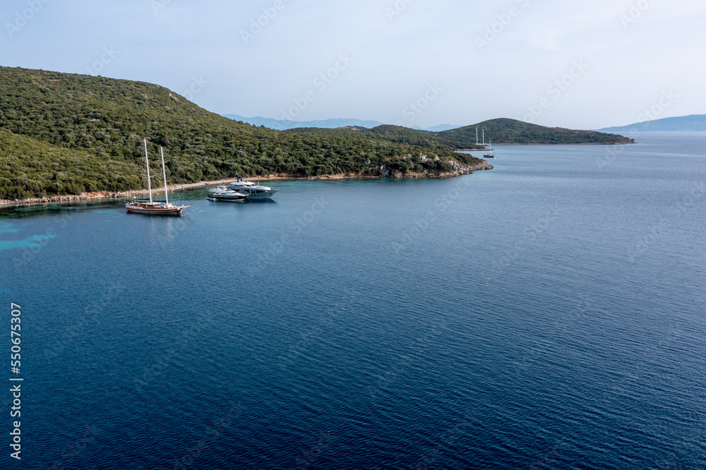 Aerial view of sailboats and luxurious yachts at the coast of Mediterranean Sea. Pine tree forest and turquoise water of Bodrum, Turkey