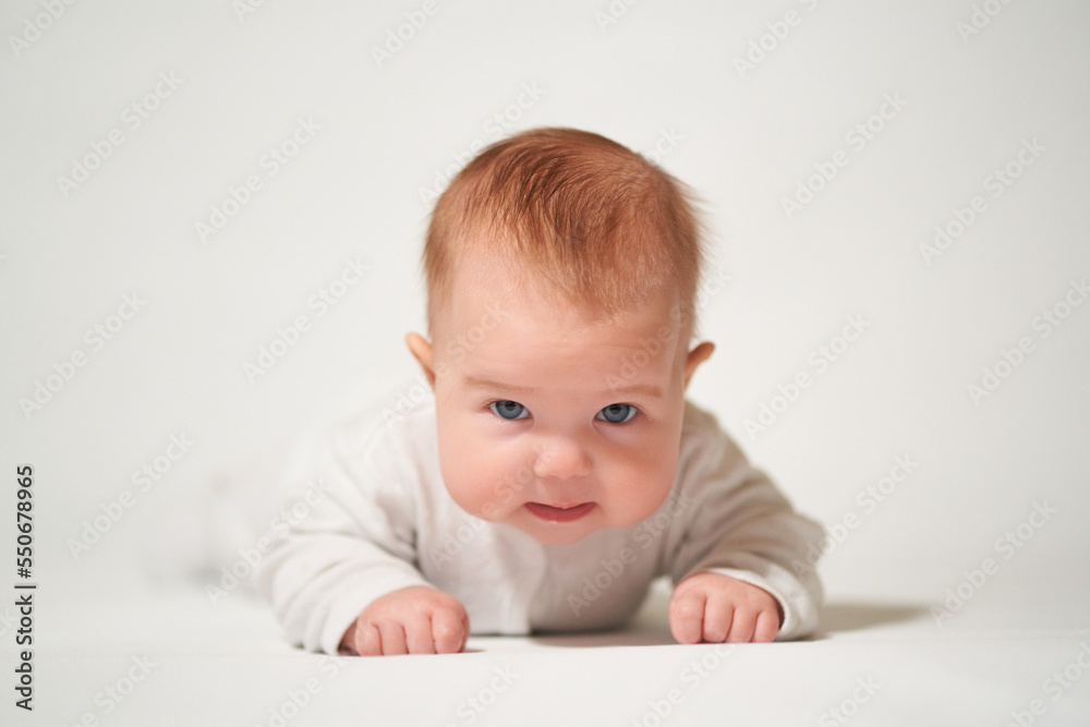 portrait of an infant lying with angry emotion on a white background portrait of an infant lying with angry emotion on a white background
