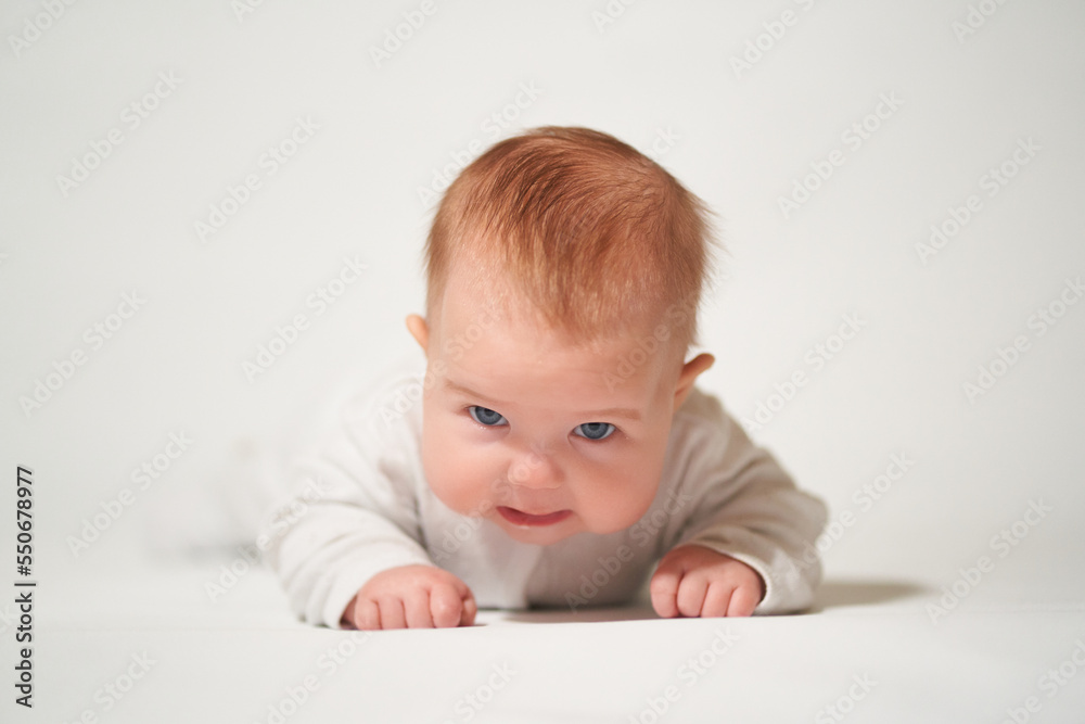 portrait of an infant lying with angry emotion on a white background portrait of an infant lying with angry emotion on a white background