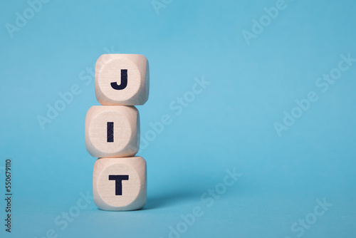 JIT, Just In Time acronym letters on wooden blocks isolated on light Blue background copy space