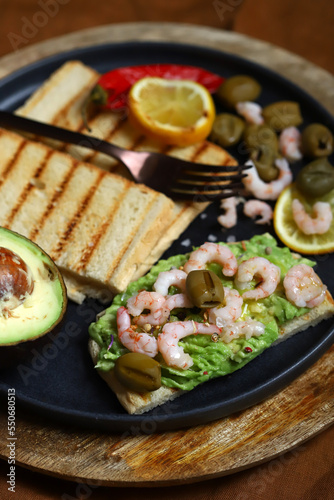 Guacamole toast with avocado, shrimp and olives. Healthy snack. Keto.