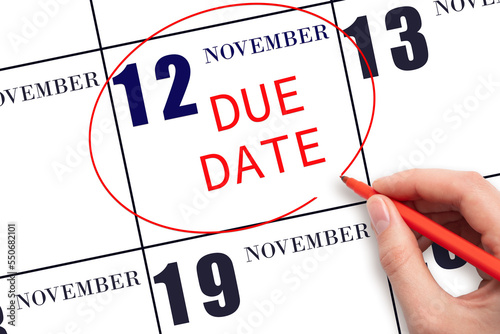12th day of November. Hand writing text DUE DATE on calendar date November 12 and circling it. Payment due date. Business concept. Autumn month, day of the year concept.