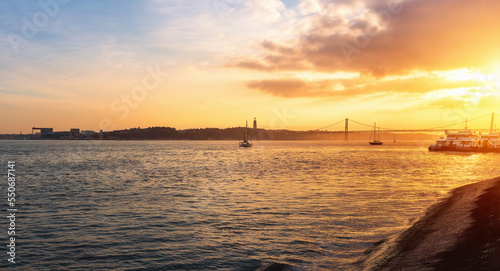 Tagus River (Rio Tejo) at sunset with 25 de Abril Bridge and Sanctuary of Christ the King on background - Lisbon, Portugal