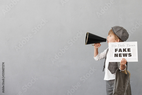 Newsboy shouting against grunge wall background. Boy selling fake news photo