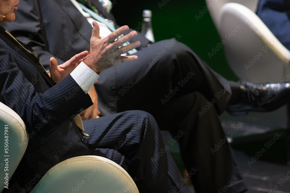 Serious men in suits sit at a conference Serious men in suits sit at a conference
