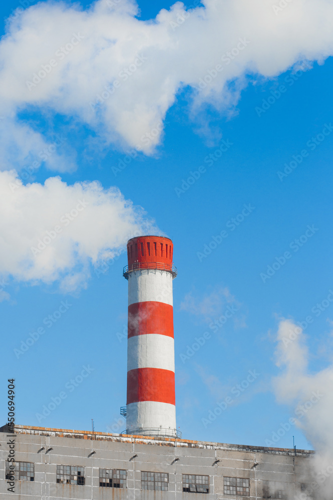 Pollution of the environment, ecology and air. Withdrawal of combustion products of soot, smoke and gases from the pipe of an industrial plant into the atmosphere against the background of a blue sky