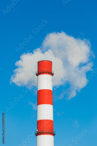 Pollution of the environment, ecology and air. Withdrawal of combustion products of soot, smoke and gases from the pipe of an industrial plant into the atmosphere against the background of a blue sky