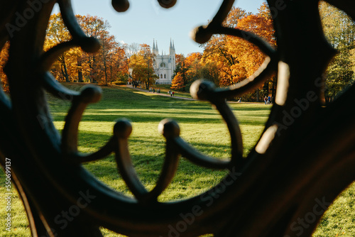 View of the autumn trees through the Gothic ornament of the ancient well, the Gothic church in the park. Autumn in a public park