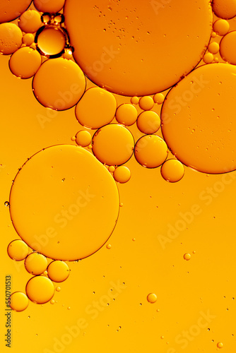 Golden yellow abstract oil bubbles or face serum background. Oil and water bubbles macro photography.