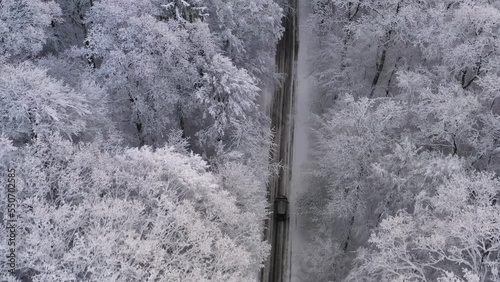 Car driving on winter country road in snowy forest, aerial view from drone in 4k. 