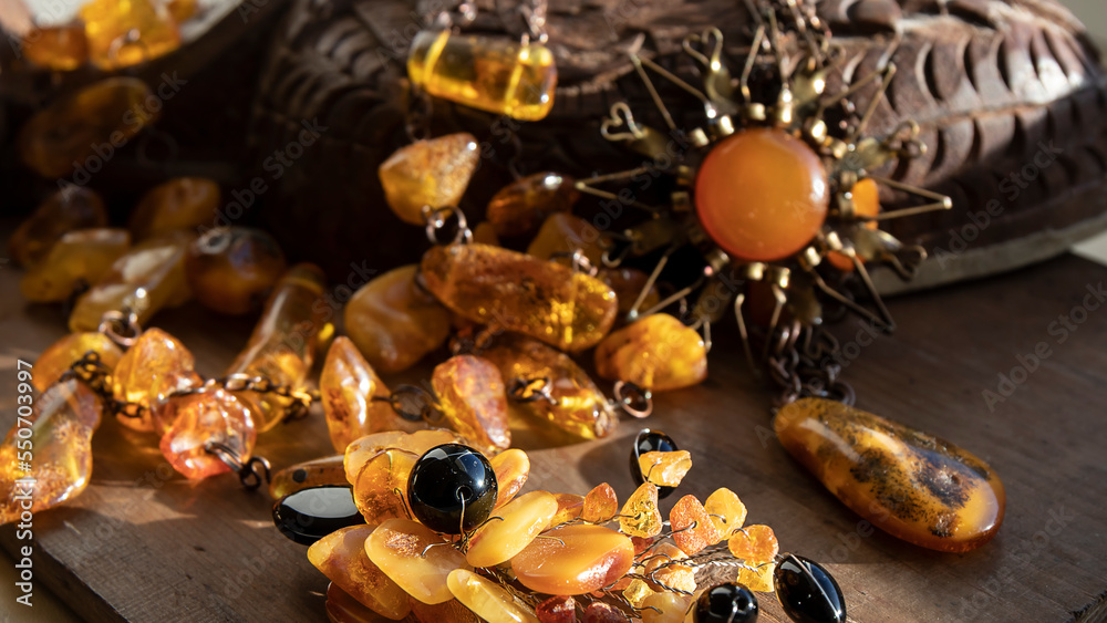 Yellow Baltic amber brooch, amber necklace and stones on the wood. Vintage amber composition. Old amber jewelry close up. Yellow Baltic amber brooch, amber necklace and stones on the wood. Vintage amber composition. Old amber jewelry close up.