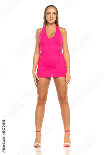 a young woman in a short pink dress posing on white background. Front view. © vladimirfloyd