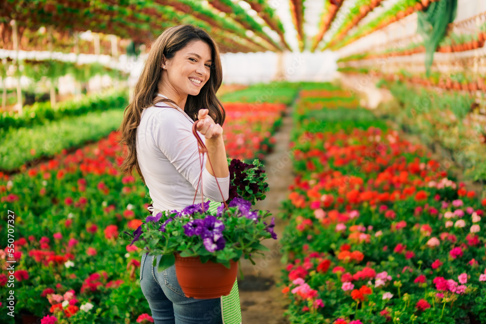 Happy nursery garden worker holding pots with flowers and relocating it. Happy nursery garden worker holding pots with flowers and relocating it.