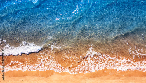 Turquoise water wave with sand beach background from aerial top view. Concept summer sunny travel image