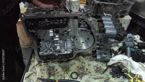 master repairs gearbox in service with hands twists bolts on table. High quality 4k footage
