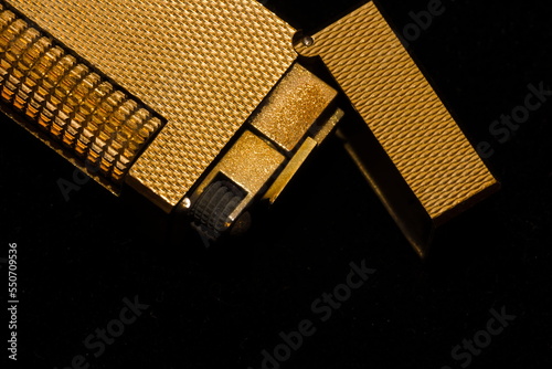 Close-up image of a vintage golden lighter on a black background