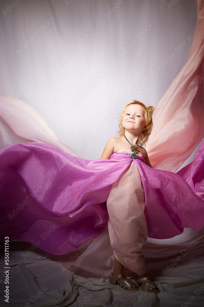 Fototapeta premium Portrait of cute kid girl posing in pink beautiful dress on a white background. Young female model looking as magic princess from fairy taly